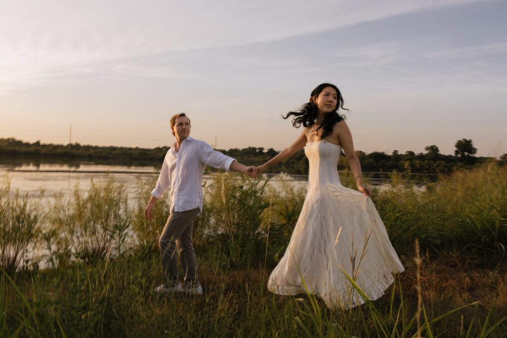 Couple holding hands by lakeside during sunrise