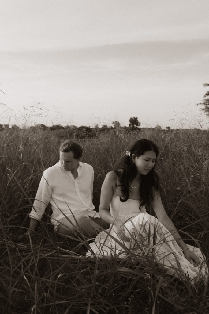 Couple sitting in a grassy field during sunrise