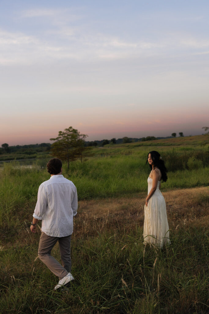 Couple walking in a field at sunset