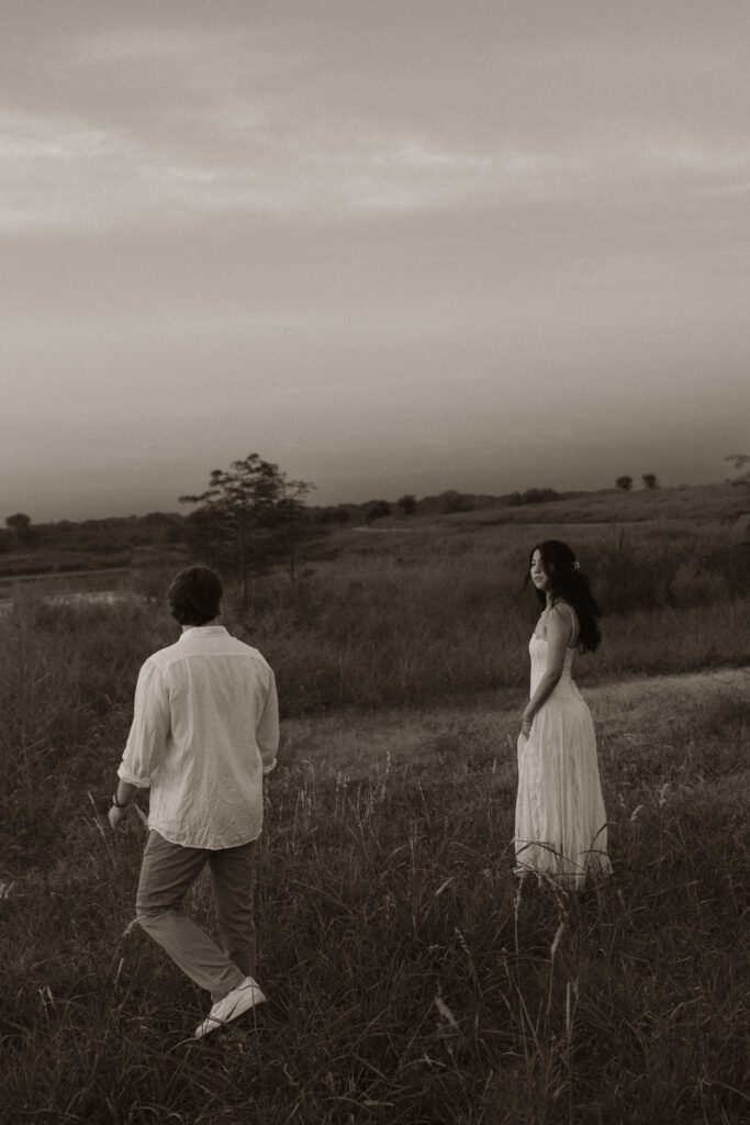 Couple walking in a grassy field at dusk.