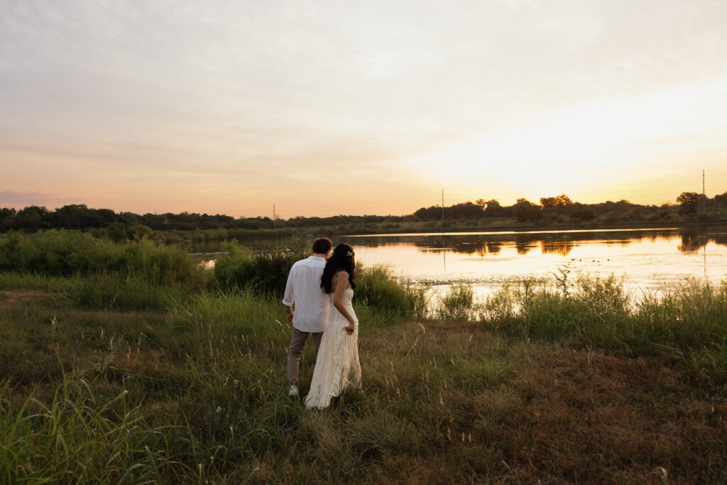 Couple walking by a serene lakeside at sunset