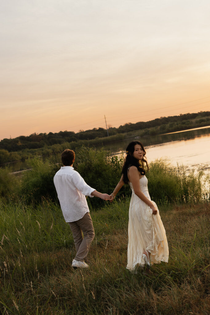 Couple walking hand in hand near a lakeside at sunrise